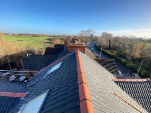 A pitched roof installed with grey and clay tiles on a residential property.