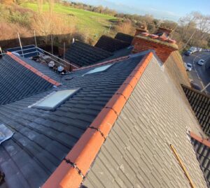 A pitched roof installed with grey and clay tiles on a residential property.