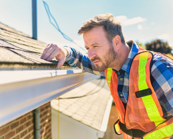 A roofer carrying out an inspection on the roof of a house.